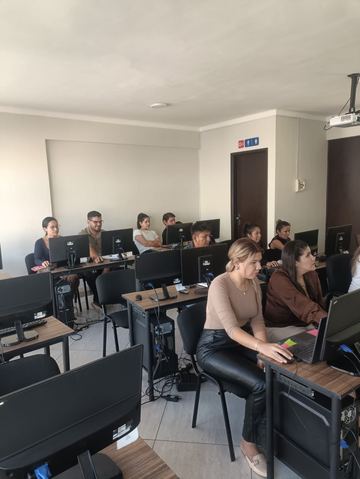 Estudiantes de INTEC trabajando en computadoras durante una clase en el aula