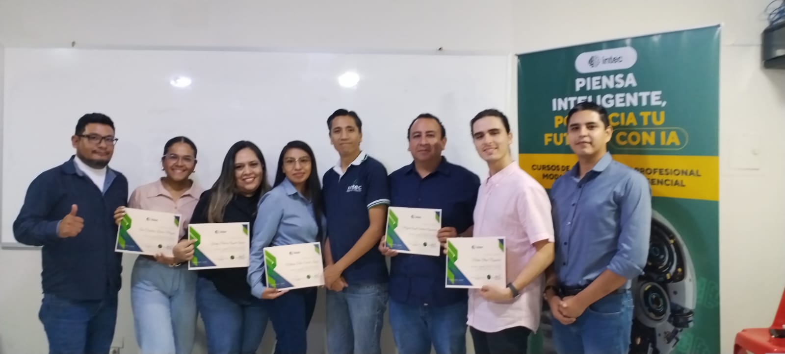 Grupo de egresados de INTEC sosteniendo sus certificados junto al banner del programa